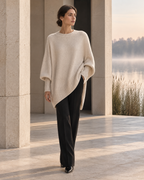Éloïse asymmetric ecru knit beside a misty riverside pavilion